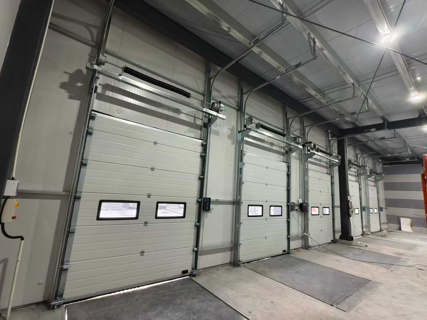 Lô hàng Cửa phân đoạn công nghiệp và Máy san lấp mặt bằng cho các dự án nhà kho